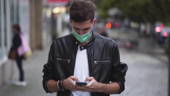 A young man with a cool hairstyle wearing a black jacket, a white t-shirt and a green protective Cov alt