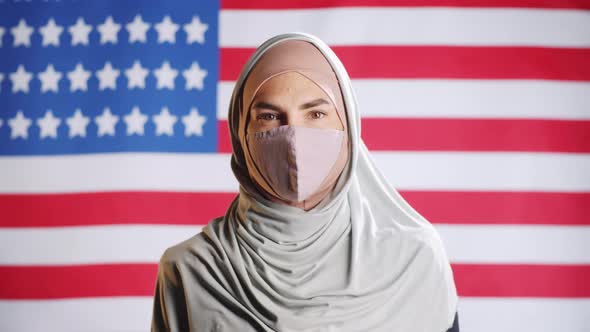 Portrait of Muslim Woman in Hijab and Face Mask on U,S, Flag alt