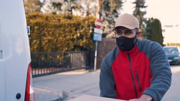Man with Face Mask Pushing Trolley with Cardboard Boxes alt
