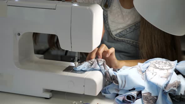 Seamstress Works at Sewing Machine Makes Straight Seams on Cloth Hands Closeup alt