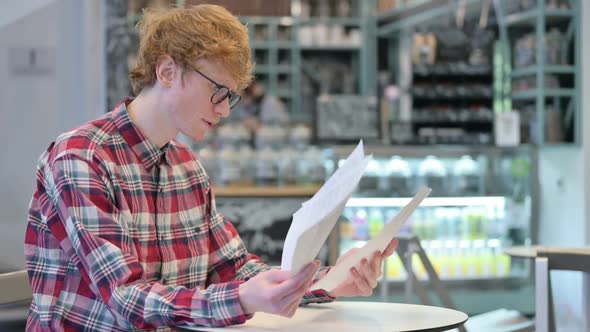 Angry Redhead Man Reacting to Loss Reading Documents alt