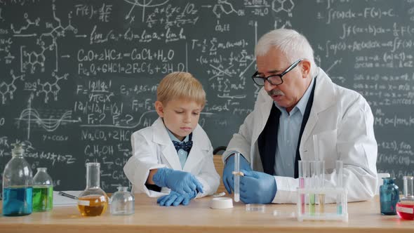 Little Boy and School Teacher Are Busy with Chemistry Experiment in Classroom alt