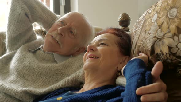 Calm senior aged couple relaxing leaning on comfortable soft couch having healthy nap together, happ