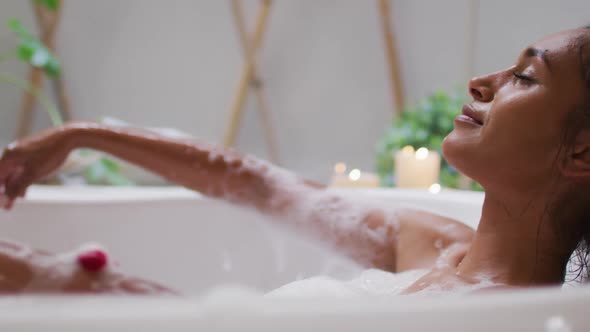 Mixed race woman lying in a bathtub at home alt