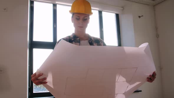 Woman in Helmet with Blueprint at New Home