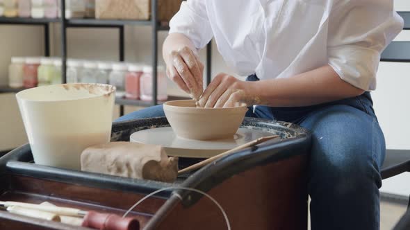 Female Potter Working with Clay on Wheel in Studio. Clay with Water Splattered Around the Potter alt