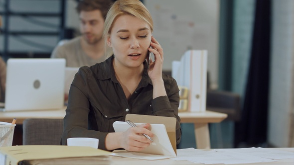 Cute Young Female Adult on Phone While Working at Desk