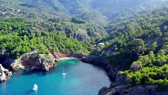 Cala Deia cove in Mallorca Spain with white yachts anchored, Aerial dolly out shot alt