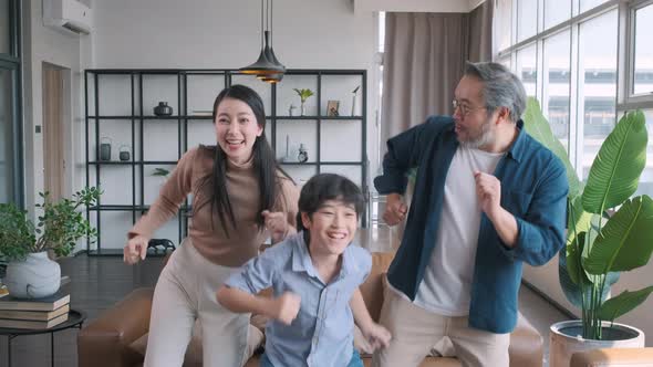 Happy asian family dancing together in the living room at home