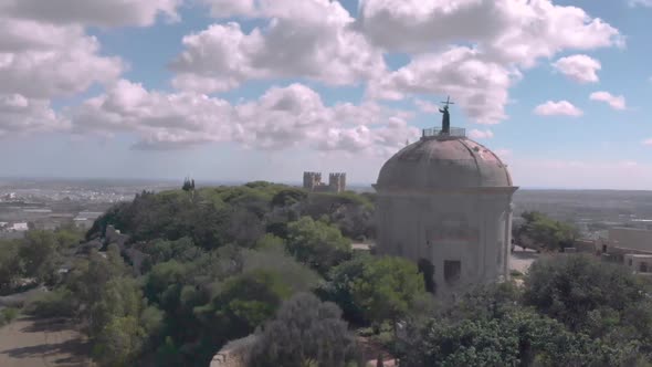 Drone shot revealing a chapel on a hill alt
