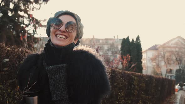 Stylish Young Woman Walking in Autumn City with Thermo Mug alt