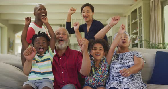 Three generation family cheering while watching TV at home alt
