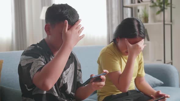 Asian Children Playing Video Games On Mobile Phone And Disappointed At Home alt