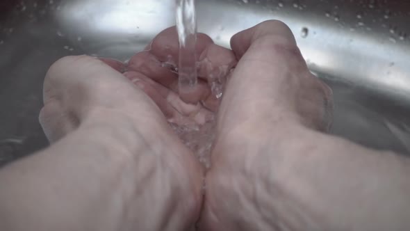 The Stream Of Water Falls From A Tap On The Hands And Scatters Lots Of Drops