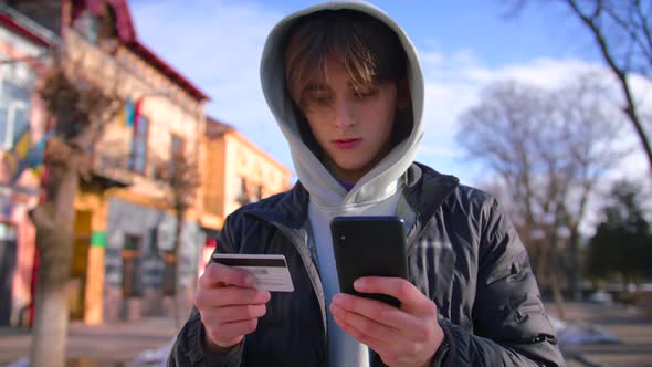 Smiling Young Male Customer Holding Credit Card and Smartphone