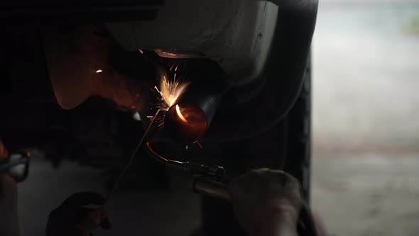 blacksmith welder works with metal steel and iron using a welding machine, bright sparks and flashes alt