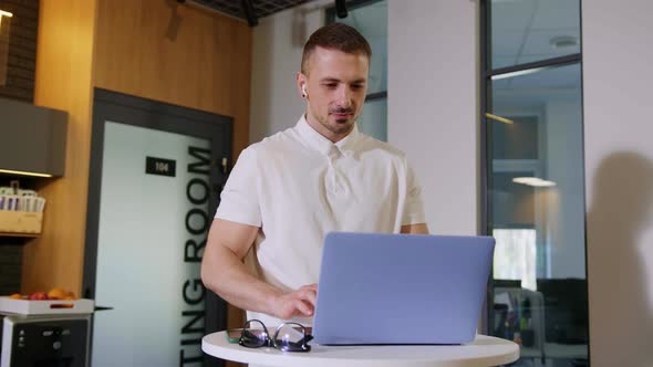 A Young Man Opens a Laptop for a Video Conference in the Office alt