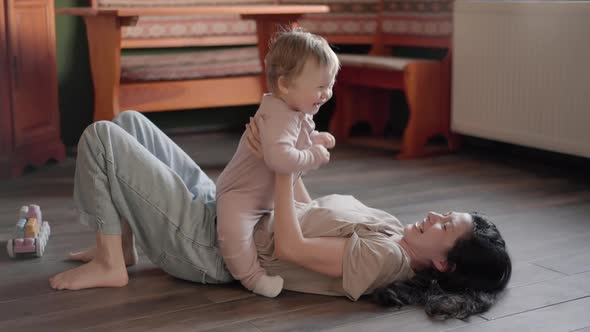 Happy Carefree Mother and Cute Small Child Daughter Tickling Laughing Having Fun Lying on Sofa and alt