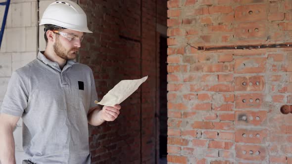 A man builder is studying a construction drawing at a construction site.