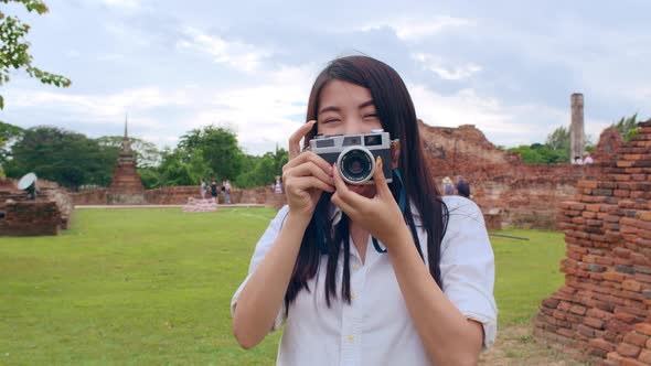 Asian backpacker blogger woman casual with camera take photo smiling traveling around pagoda.