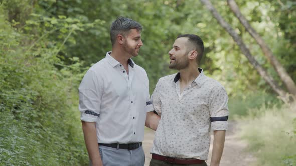 Gay couple during a photo shoot before their wedding in a forest alt