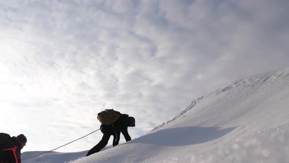 Three Alpenists in Winter Climb Rope on Mountain. Travelers Climb Rope To Their Victory Through Snow alt