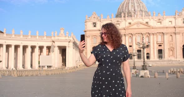 Young Caucasian female makes selfie in front of Vatican cathedral in Rome
