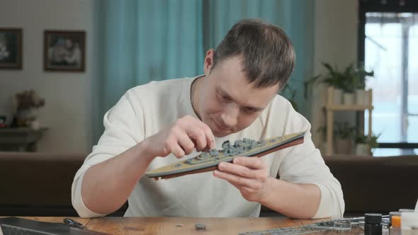 Adult European man collects plastic model of historic ship.