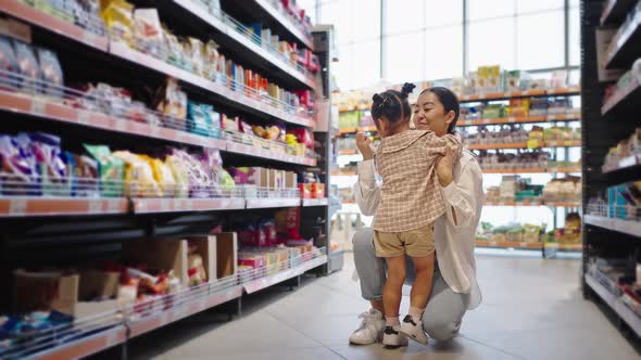 Happy Mother Gives Present Hugging Daughter in Supermarket alt