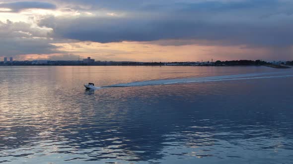 A Small Motor Boat Moves Quickly Through the Water. Evening Sunset on the Sea alt