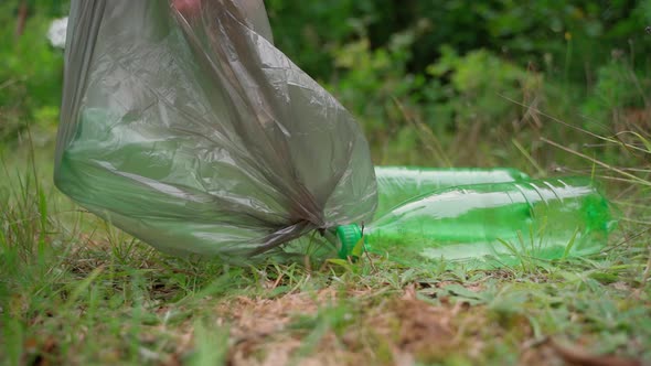 Worker cleaner remove garbage rubbish in bag at forest meadow. Sunny day. Slow motion. Closeup alt