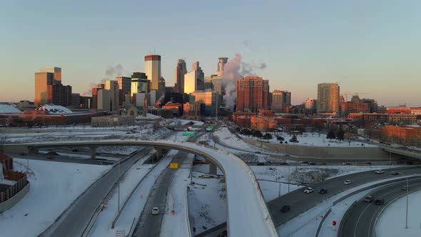 Minneapolis downtown skyline aerial footage during a winter golden hour, highways covered with snow, alt