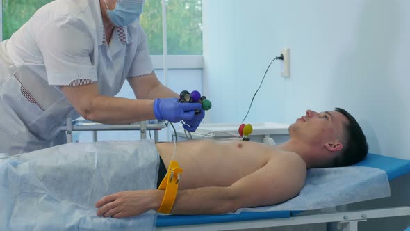 Nurse Attaching ECG Electrode Pads To Male Patient's Chest alt