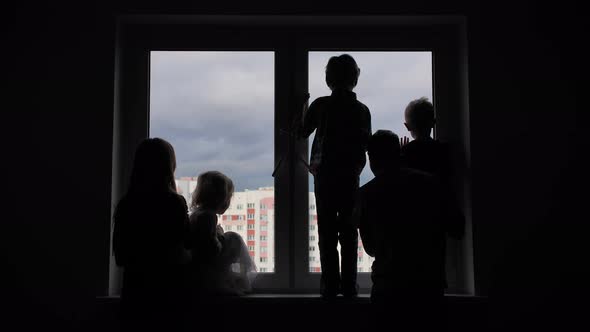 Silhouette of a Large Family on the Background of a Window in a New Apartment. Quarantine Concept. alt