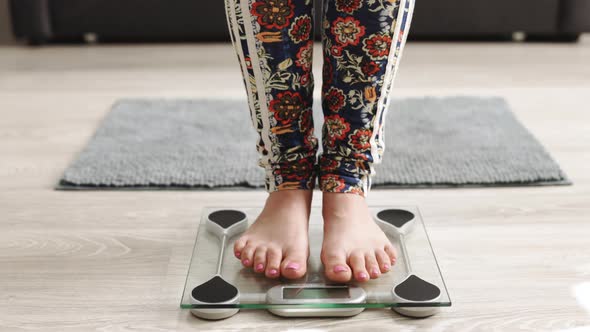 Closeup of Barefoot Woman Using Digital Scales and Checking Her Weight