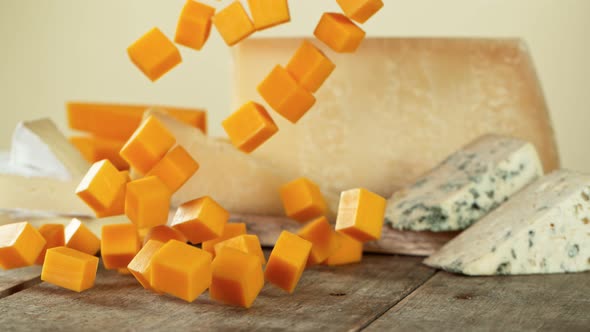 Super Slow Motion Shot of Cheddar Cubes Falling on Wooden Board at 1000 Fps. alt