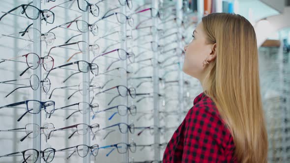 Beautiful girl choosing new spectacles.  alt