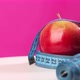 An Apple on a Pink Background is Wrapped in a Centimeter Tape - VideoHive Item for Sale