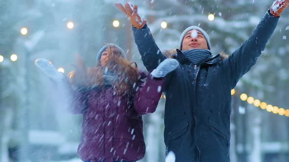 Funny Couple in Jackets and Hats Throws Snow in Winter Park