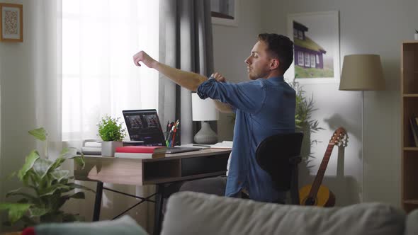 Young Handsome Man Starts Working While Sitting at His Desk in His Living Room alt