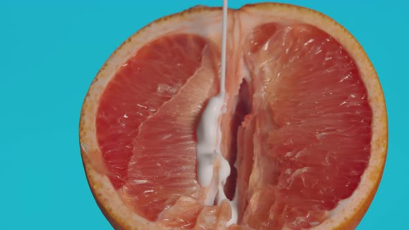Closeup of a Half of a Grapefruit Sticky White Liquid Pouring Onto It alt