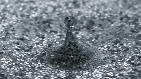 Water drop making ripple on water filled with glitter, Slow Motion alt