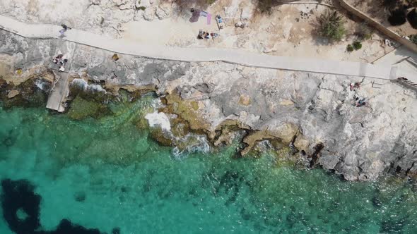 Rocky sea shore eroded by the Mediterranean turquoise sea in Sliema, Malta - Rocket aerial shot alt
