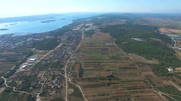 Flying above green fields and remote houses on dalmatian coast, Croatia alt