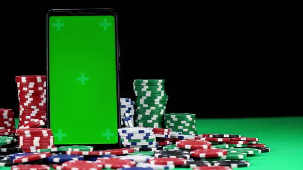 Close-up of Chroma Key Mobile in Vertical Orientation Among a Pile of Poker Chips alt