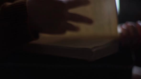 Closeup Hands of Unrecognizable Young Woman Flipping Through Pages of Old Frayed Book at Home in alt
