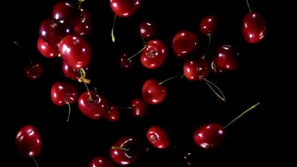 Top View of the Red Cherries Bouncing Up on a Black Background in Slow Motion alt