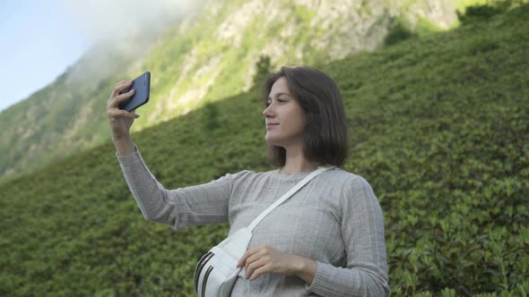 Young Blogger Woman Recording Selfie Video While Hiking on Top of Mountain. Lifestyle Travel Vlog alt