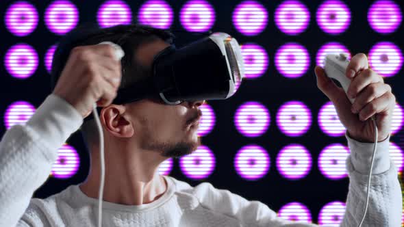 Man in Virtual Reality Glasses Dries Hair with Hair Dryer Using Joystick