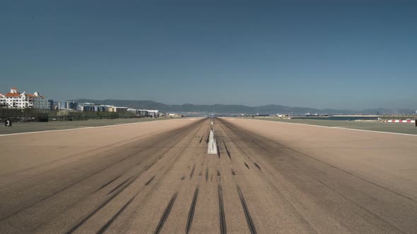 Empty runway with tire marks at Gibraltar airport, cloudless sky above. alt